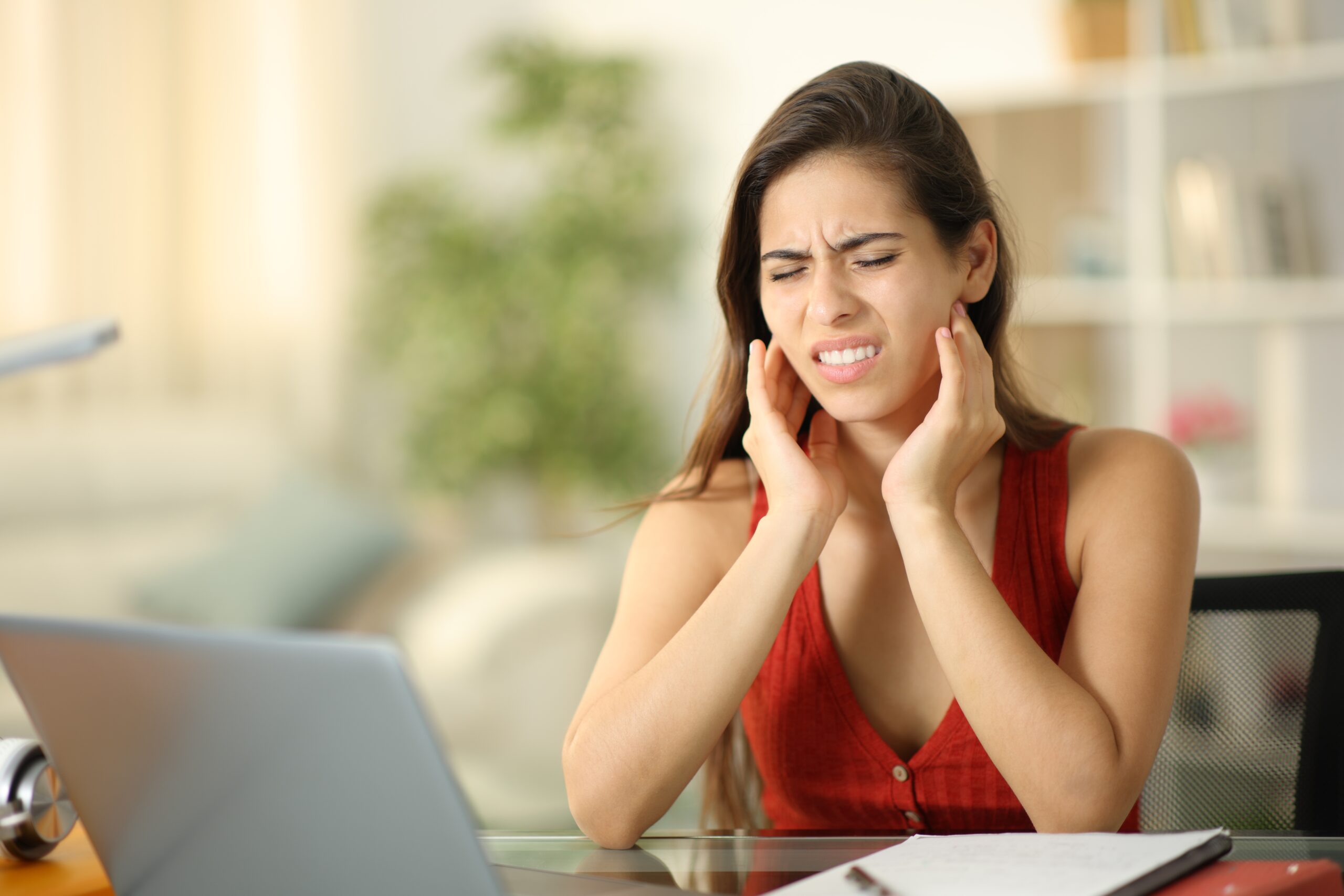 Stressed student suffering temporomandibular ache at home