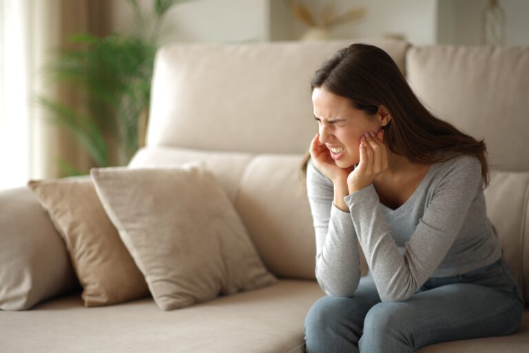 Woman suffering tmj syndrome complaining alone sitting on a couch at home