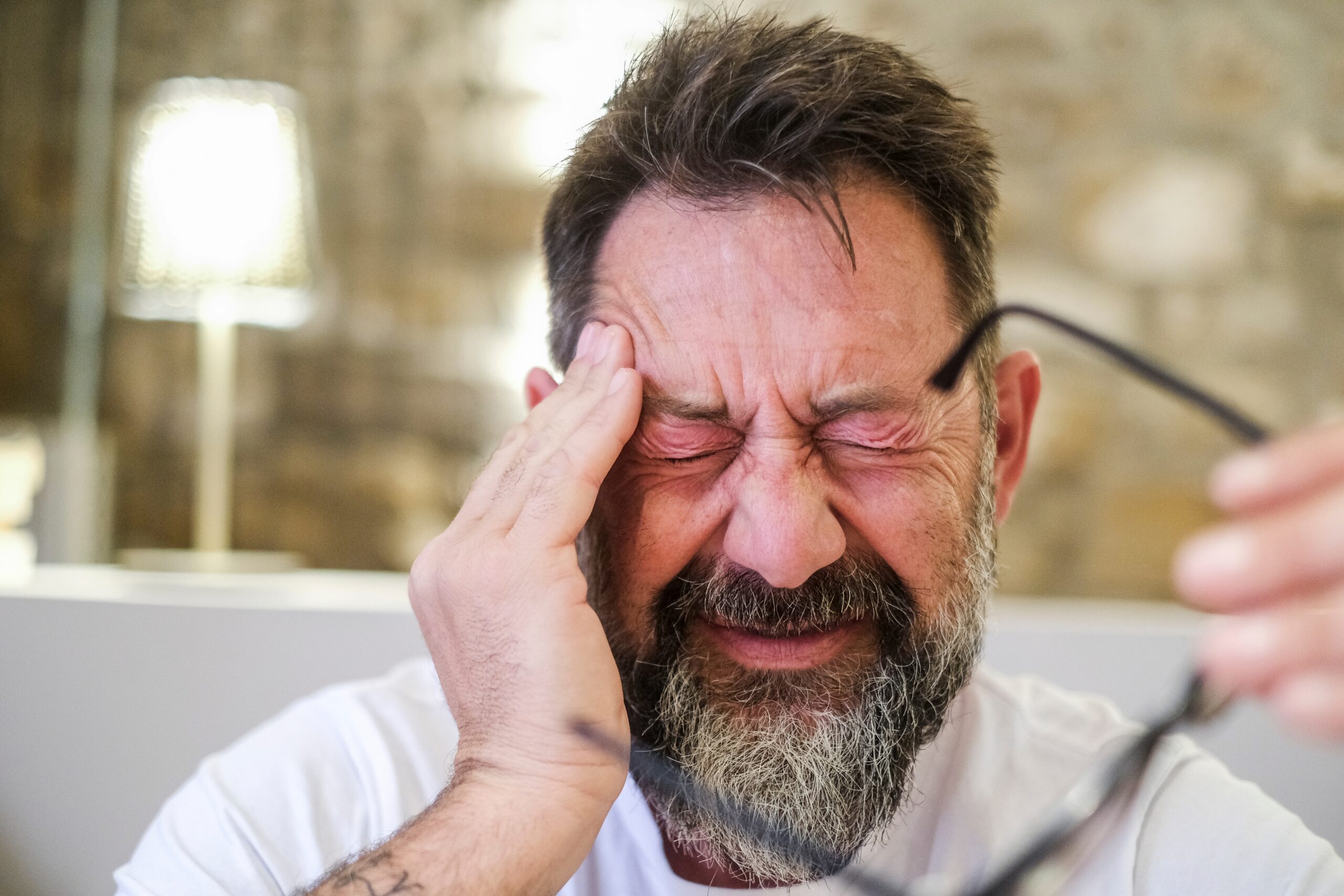 Man suffering from severe headache and emotional distress, massages his forehead in an effort to relieve the TMJ pain