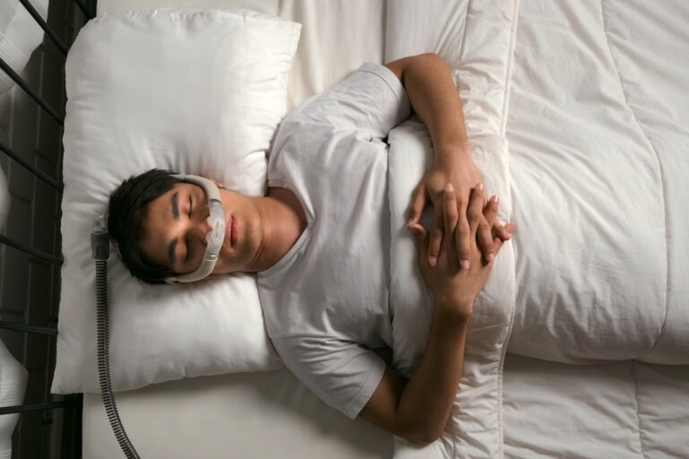 Man sleeping on back with CPAP mask to treat snoring and obstructive sleep apnea (OSA)