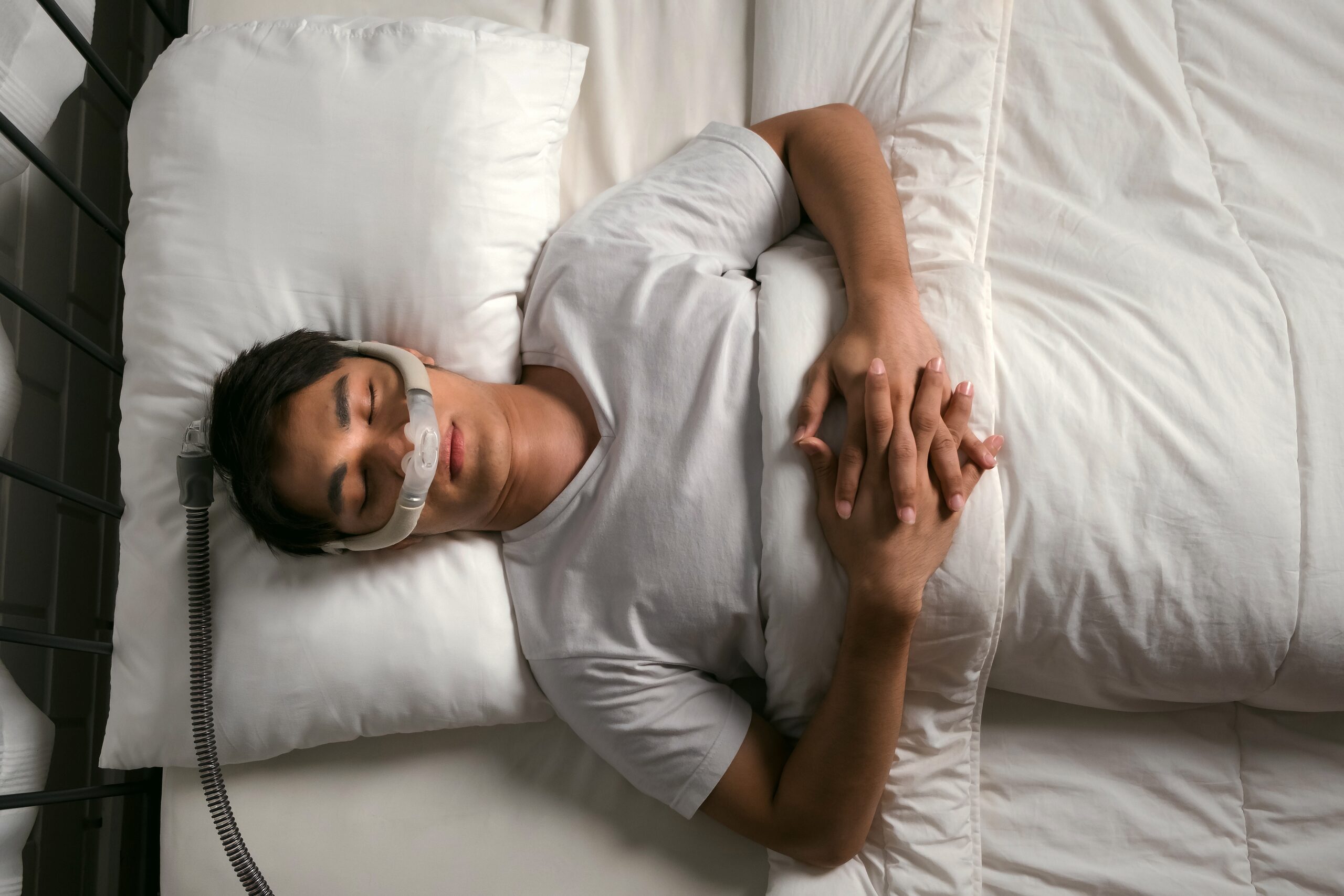 Man sleeping on back with CPAP mask to treat snoring and obstructive sleep apnea (OSA)