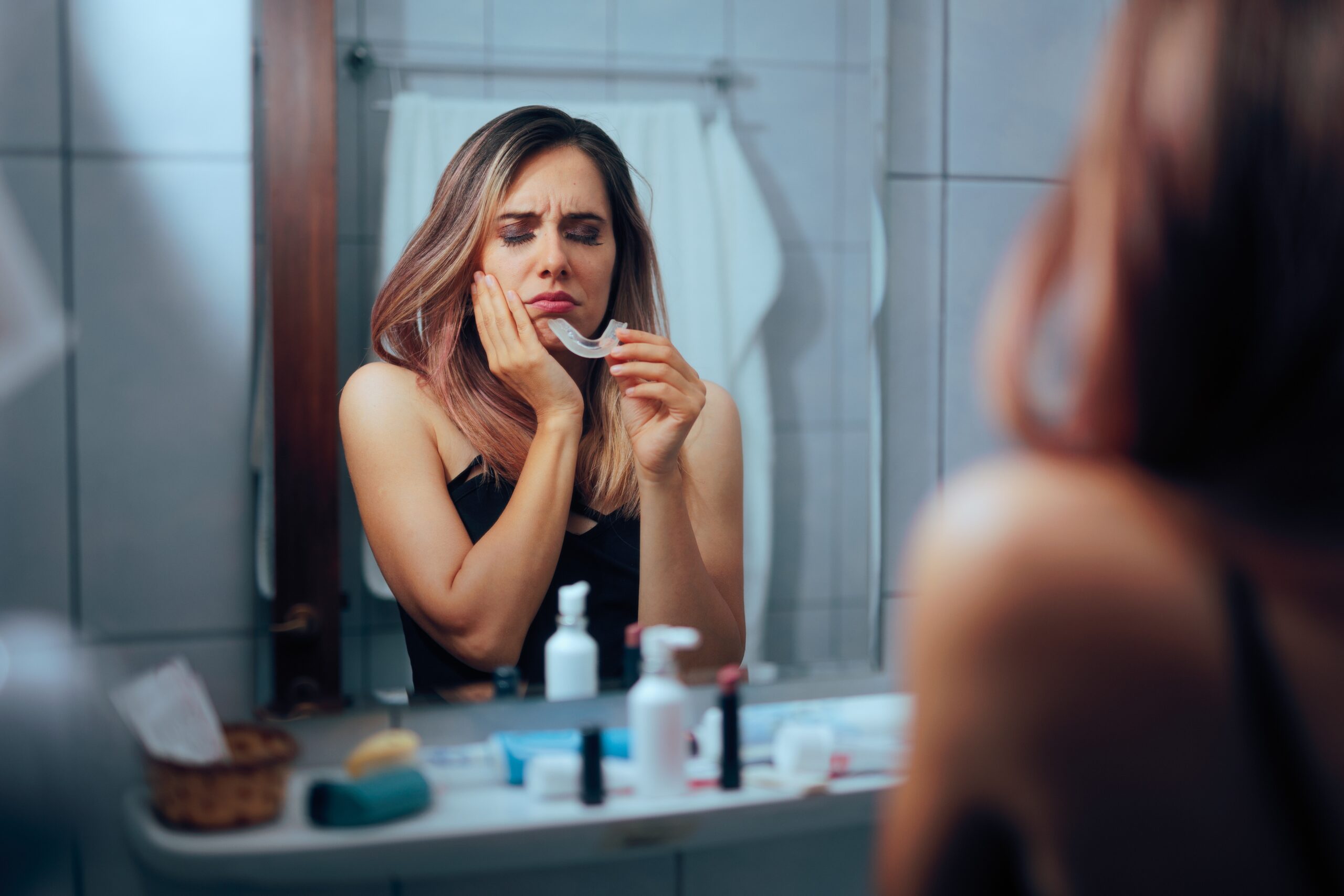 woman in bathroom suffering from TMJ related jaw pain