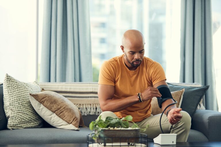 man on couch taking his blood pressure